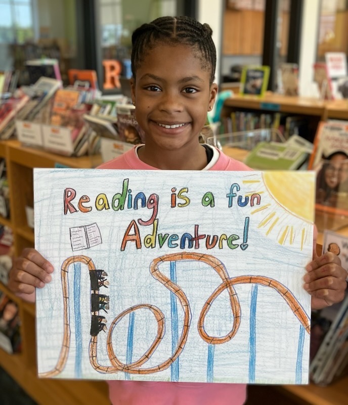 A student shows her handmade artwork that will hang in a school library.