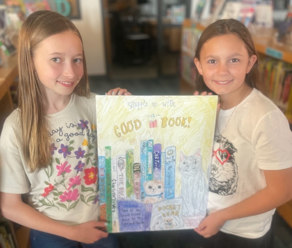 Two students hold hand-drawn artwork.
