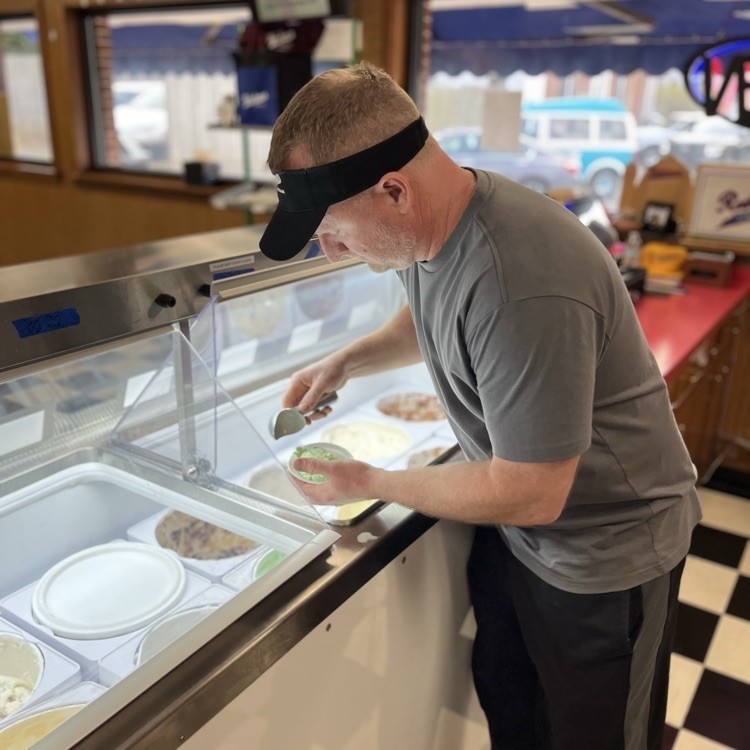A man scoops up a dish of mint chocolate chip ice cream.