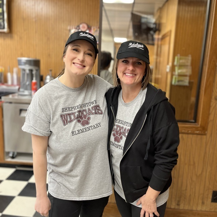 Two ladies smile for a photo before scooping ice cream for a fund raiser.