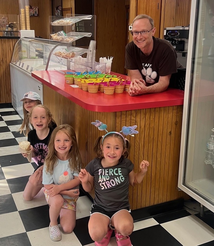 A man stands behind an ice cream counter where students eagerly grabbed a cone of ice cream.