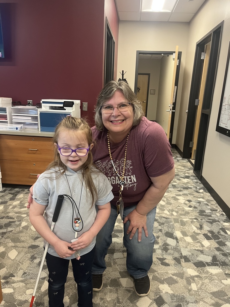 A lady poses with a young student after giving her a gift.