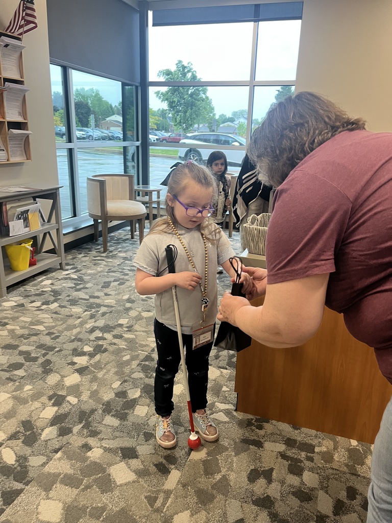 A lady hands a young student a gift bag.