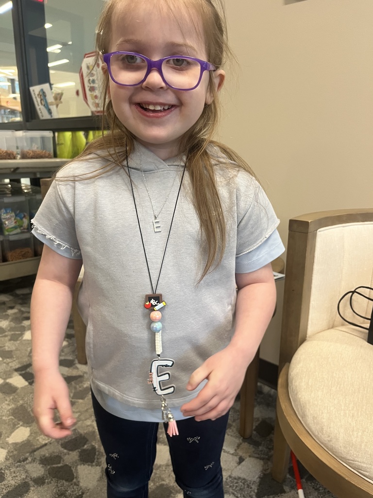 A young student proudly shows off her new lanyard.