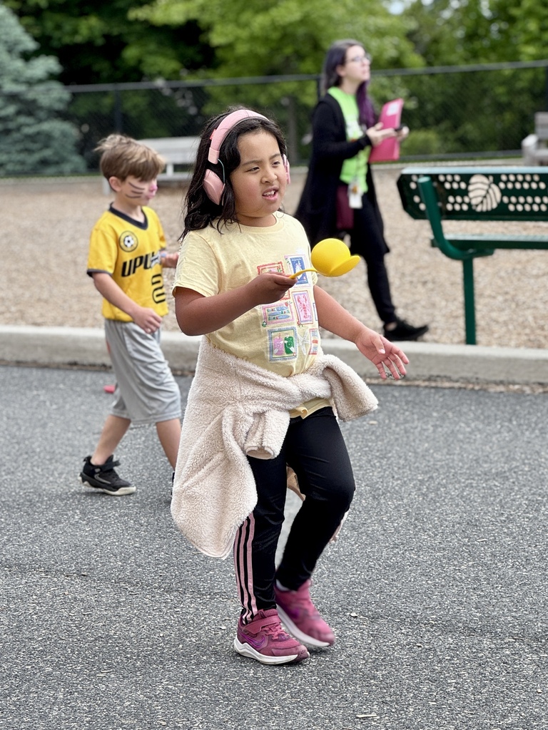 A young girl holds a large plastic ball on a plastic spoon.