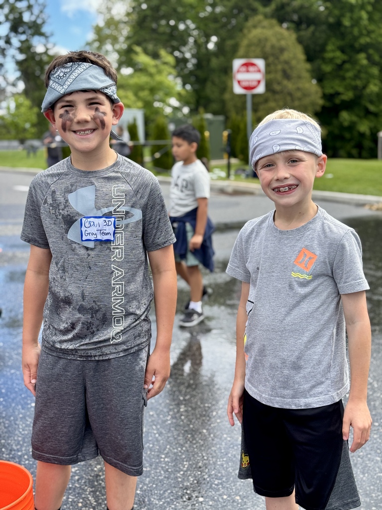 Two young boys stand together and smile.