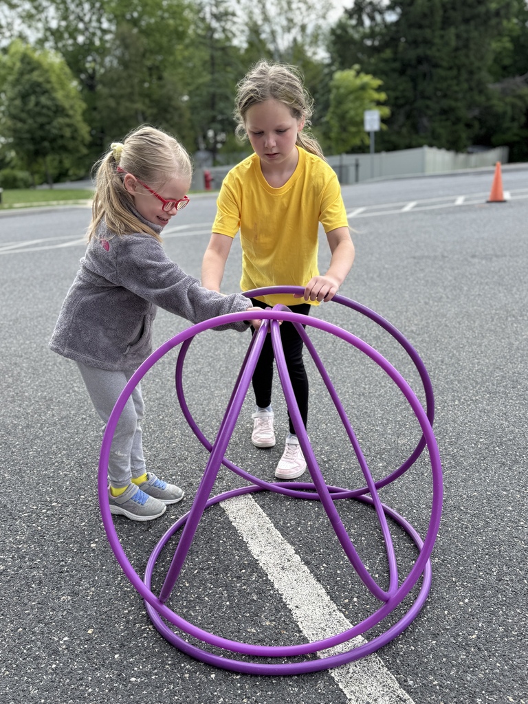 Two young students work together to pile hoops into a pyramid.