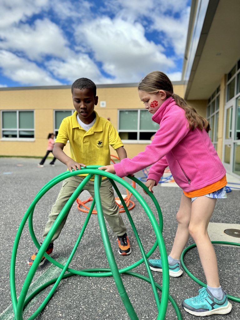 Two young students work together to pile hoops into a pyramid.