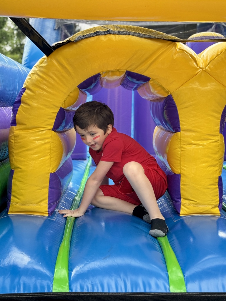 A young boy slides down a bouncy house.