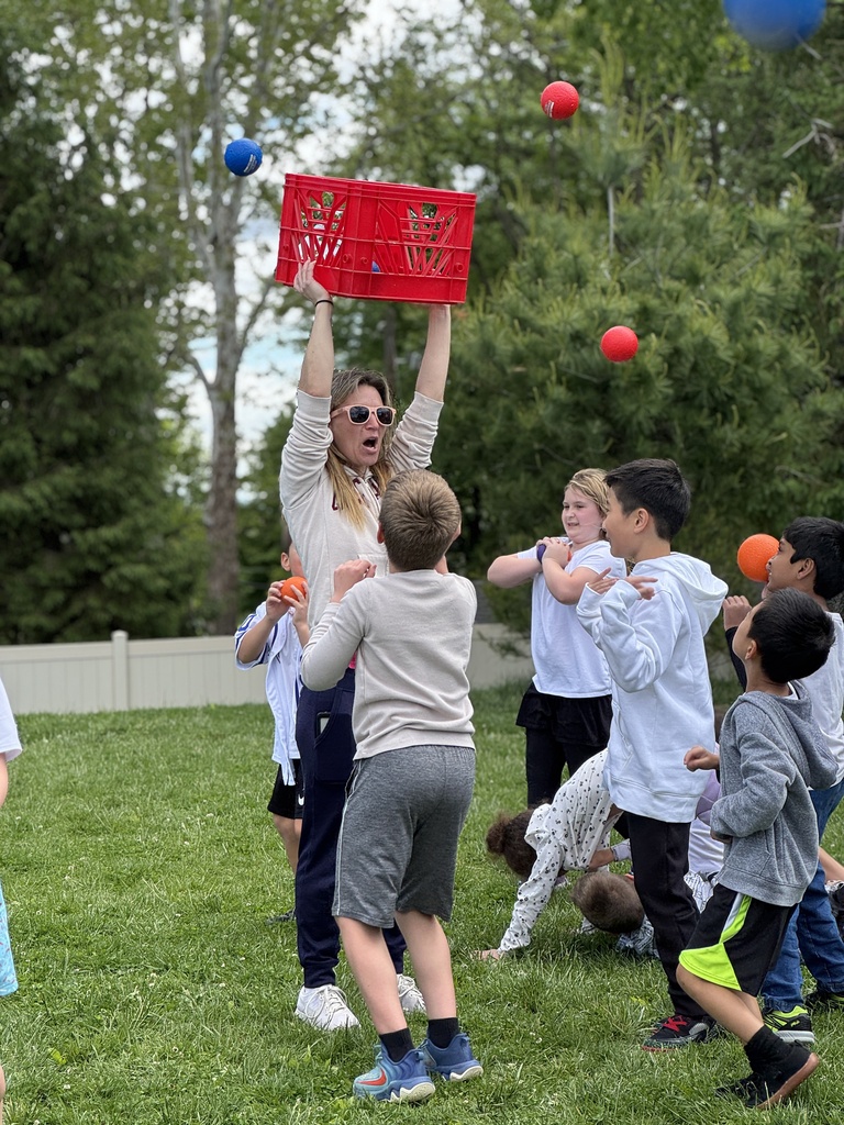 A group of students try to catch plastic balls that a teacher is dumping out of a bin from overhead.