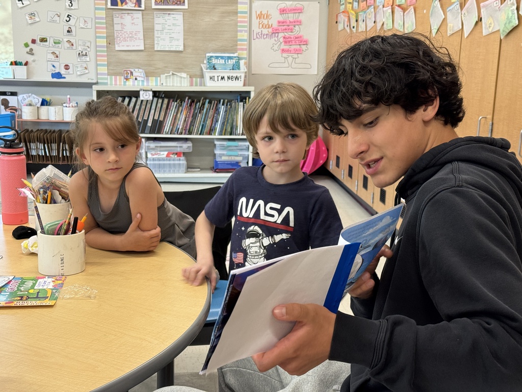 A high school student reads to elementary students.