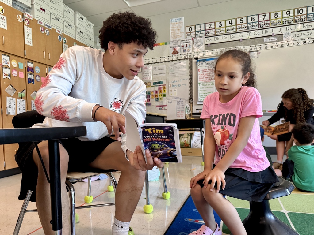 A high school student reads to elementary students.