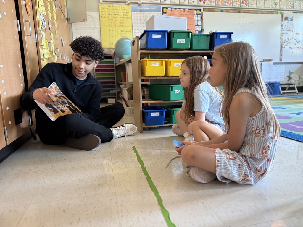 A high school student reads to elementary students.