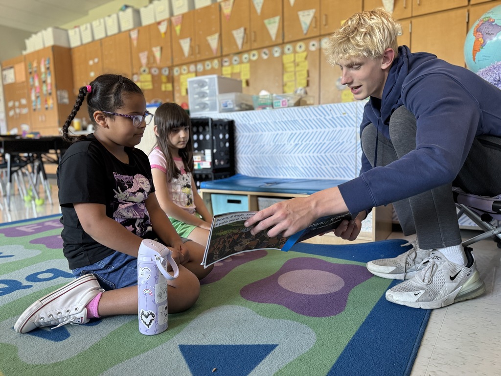 A high school student reads to elementary students.