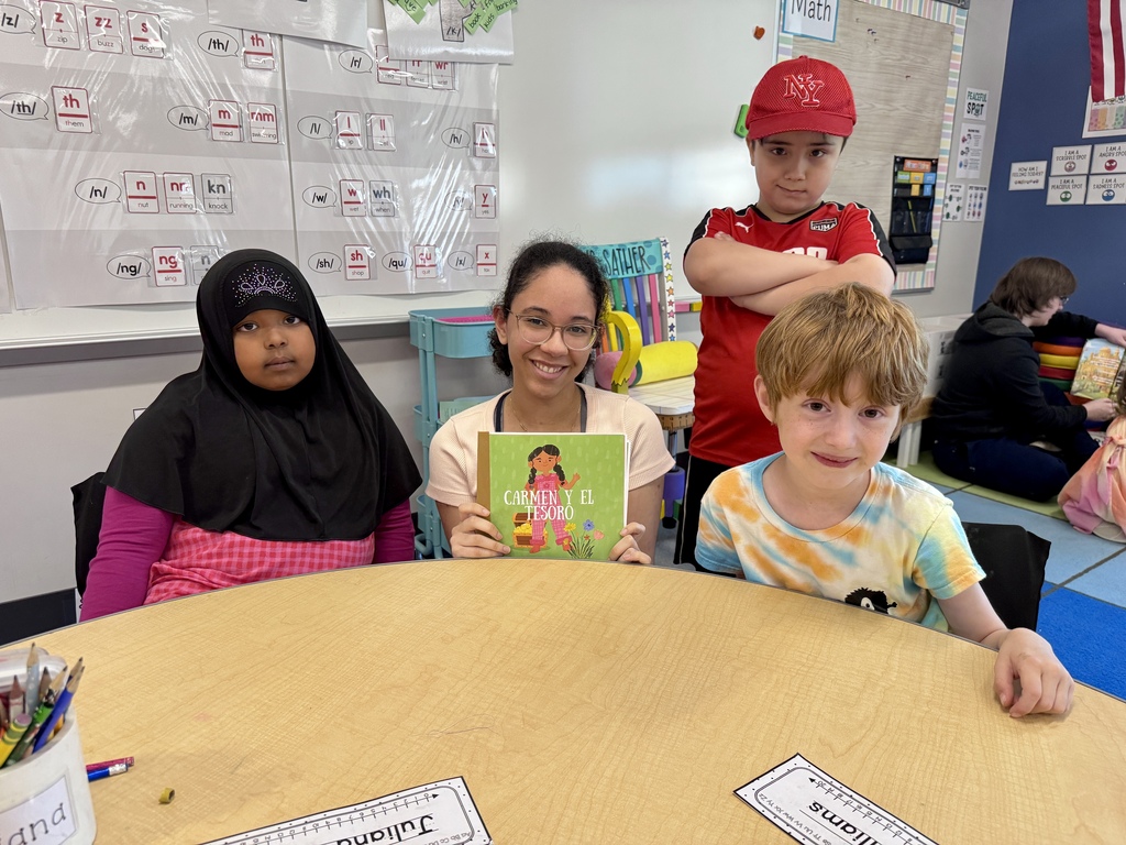 A high school student sitting at a table after reading a book to younger students.
