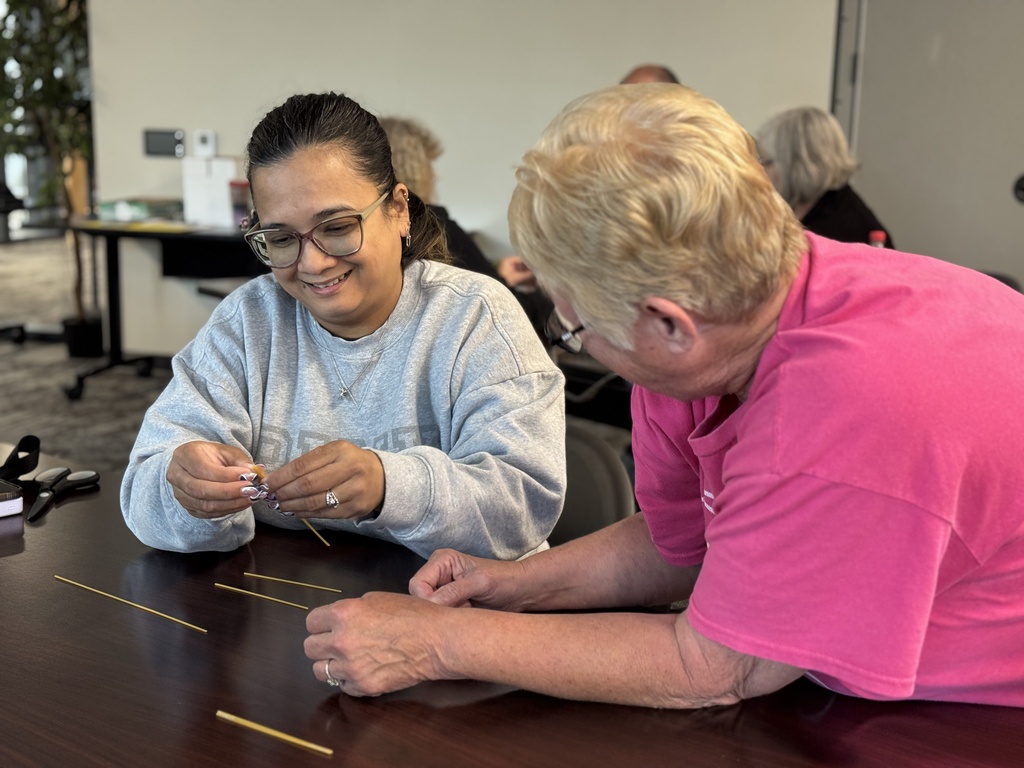 A group of adults around a table working together to build the tallest tower with random supplies.