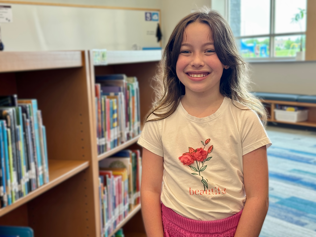 A young student standing in a school library.