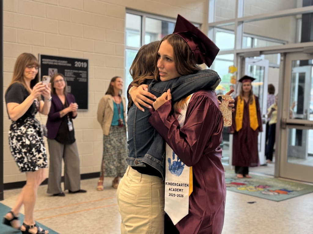 A mom hugs a graduate in a cap and gown.