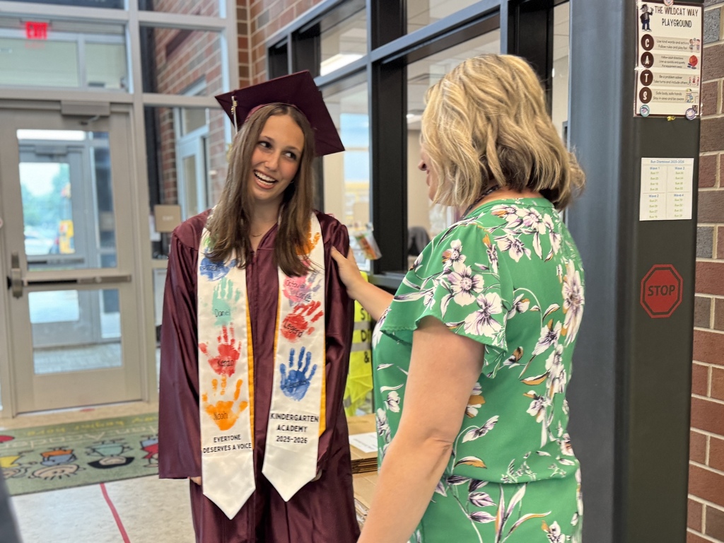 A graduate in a cap and gown talks to a former teacher.