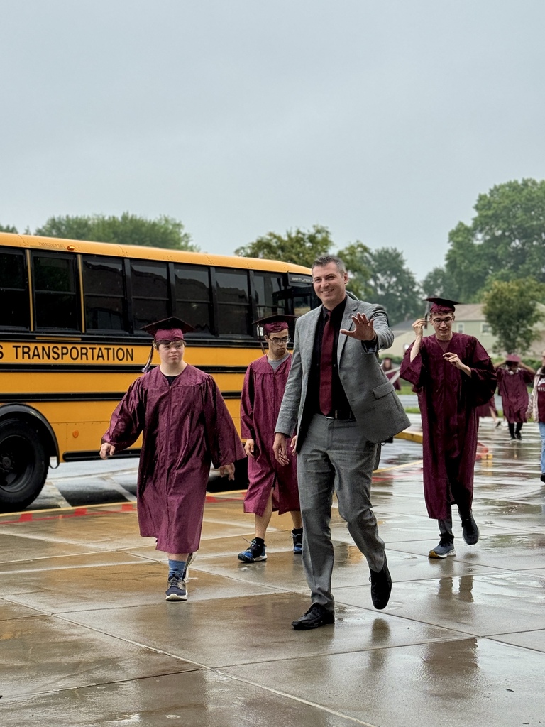 A principal walks alongside graduates.