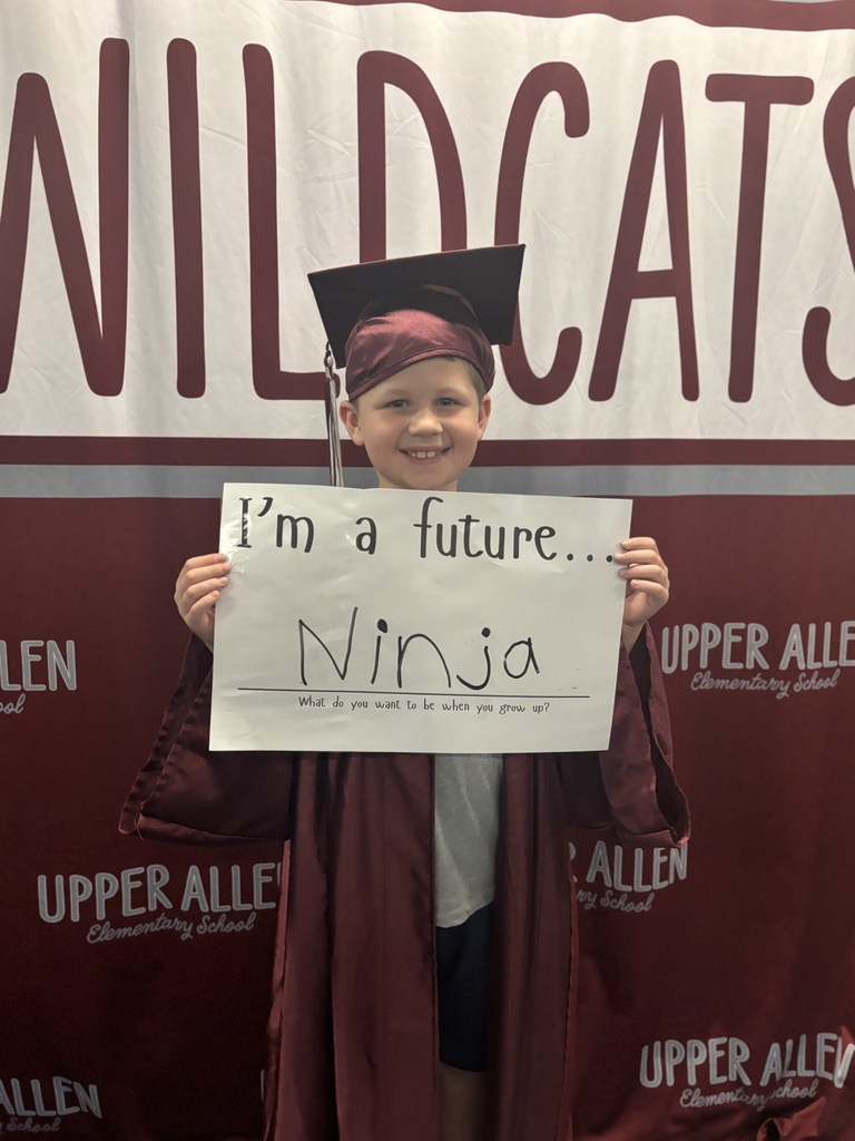 Young student wearing a cap and gown and holding a sign that says I'm a future Ninja.