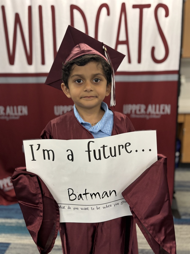 Young student wearing a cap and gown and holding a sign that says I'm a future Batman.
