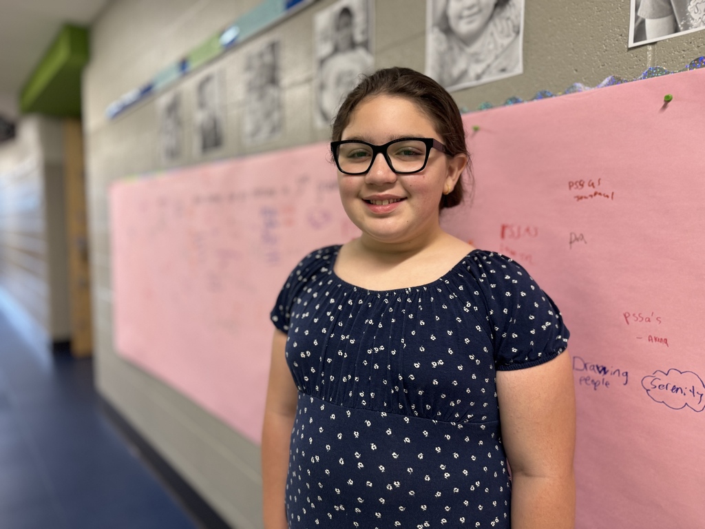 A student standing in front of a pink wall.