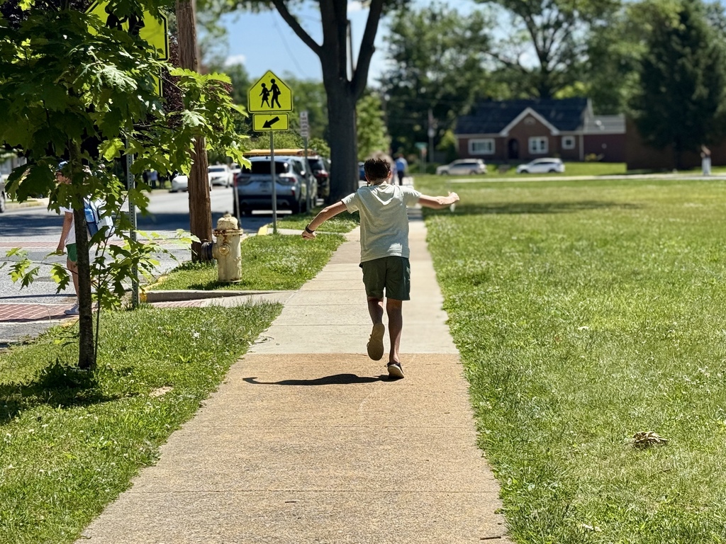 A student runs down a sidewalk on the last day of school.