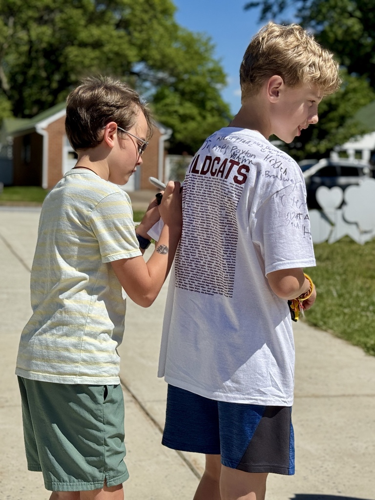 One student signs another student's tshirt.