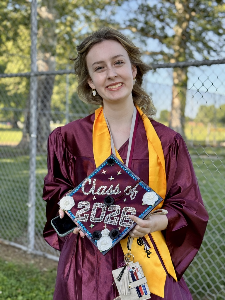 A graduate holding a decorated cap.