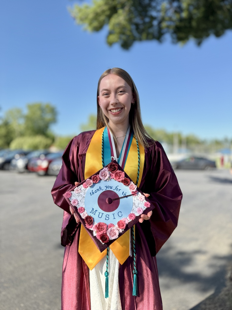 A graduate holding a decorated cap.