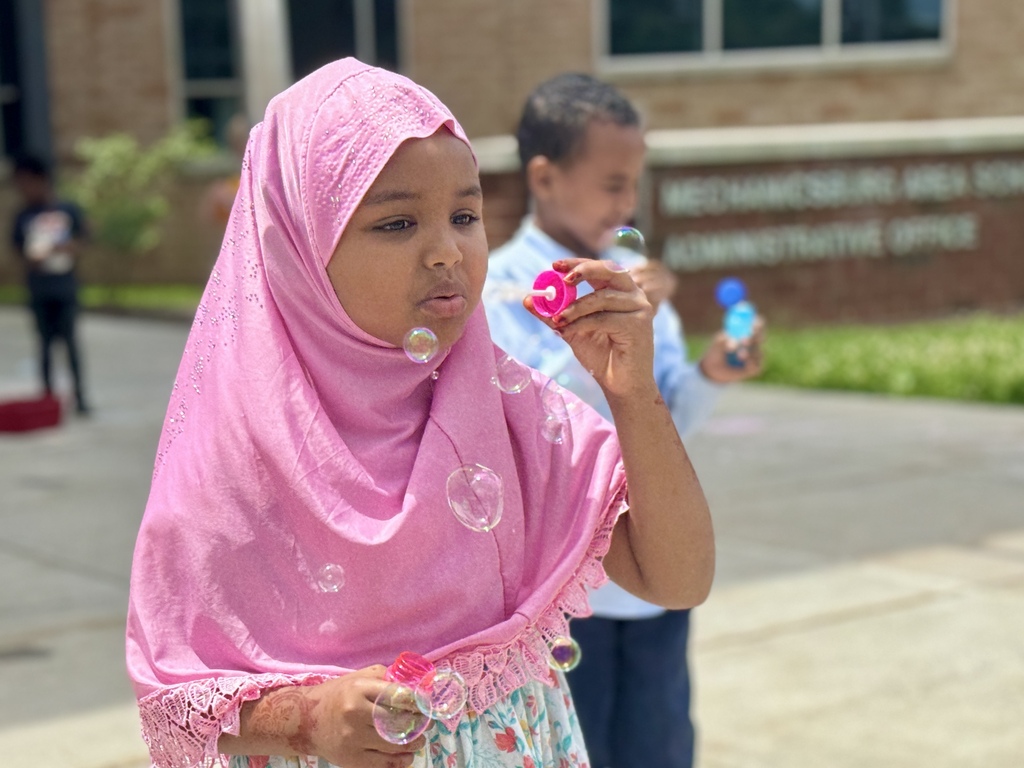 Young students blow bubbles.