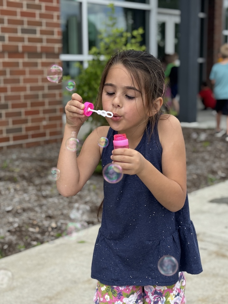 A young girl blows bubbles.