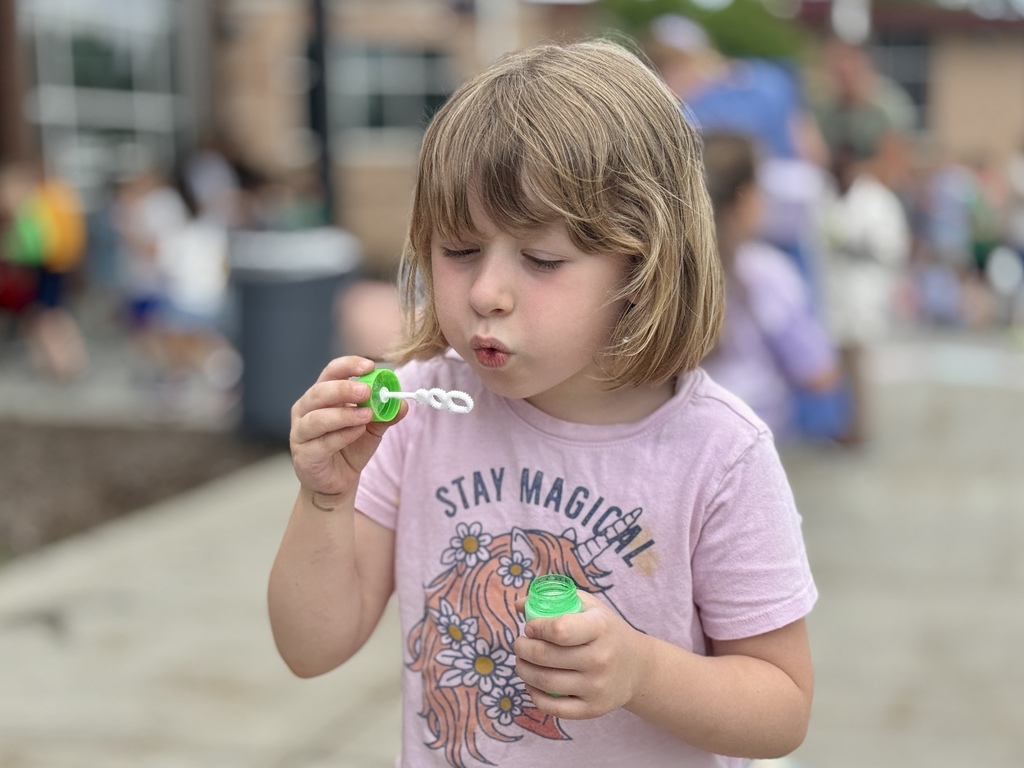 A young girl blows bubbles.