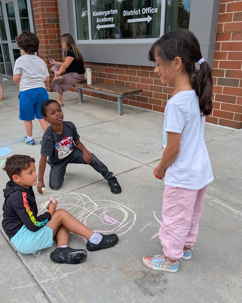 Young students draw on the sidewalk with chalk.