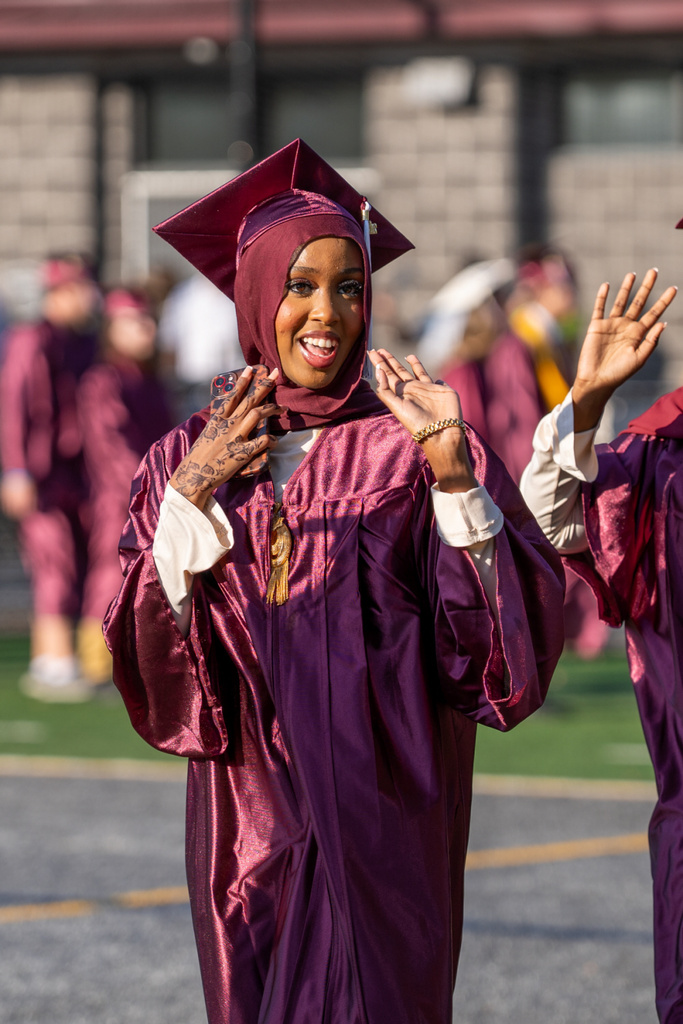 A graduate proudly waves to her supporters.