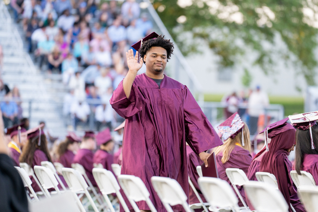 A graduate waves to supporters after receiving his diploma.