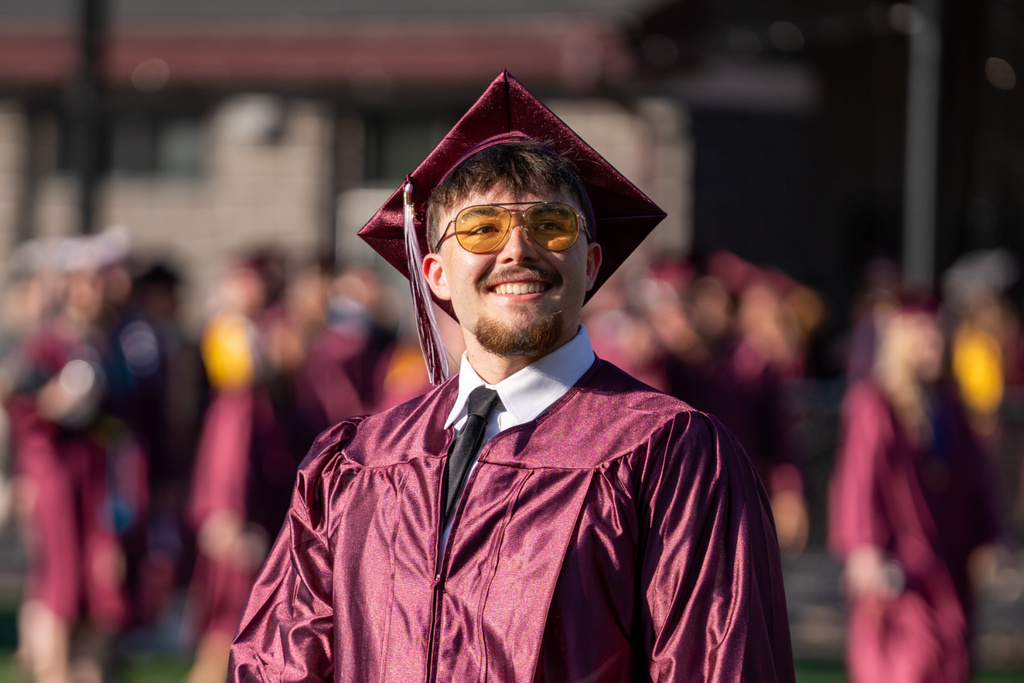 A graduate proudly smiles at his supporters.