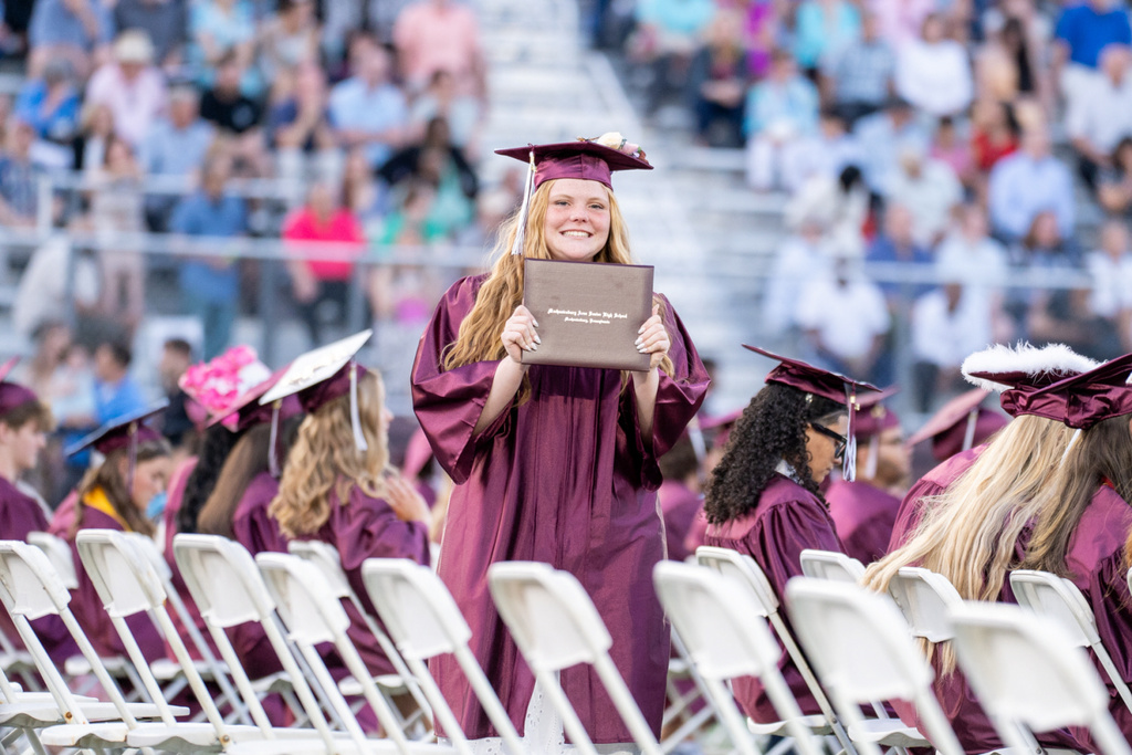 A graduation proudly holds their diploma after crossing the stage.