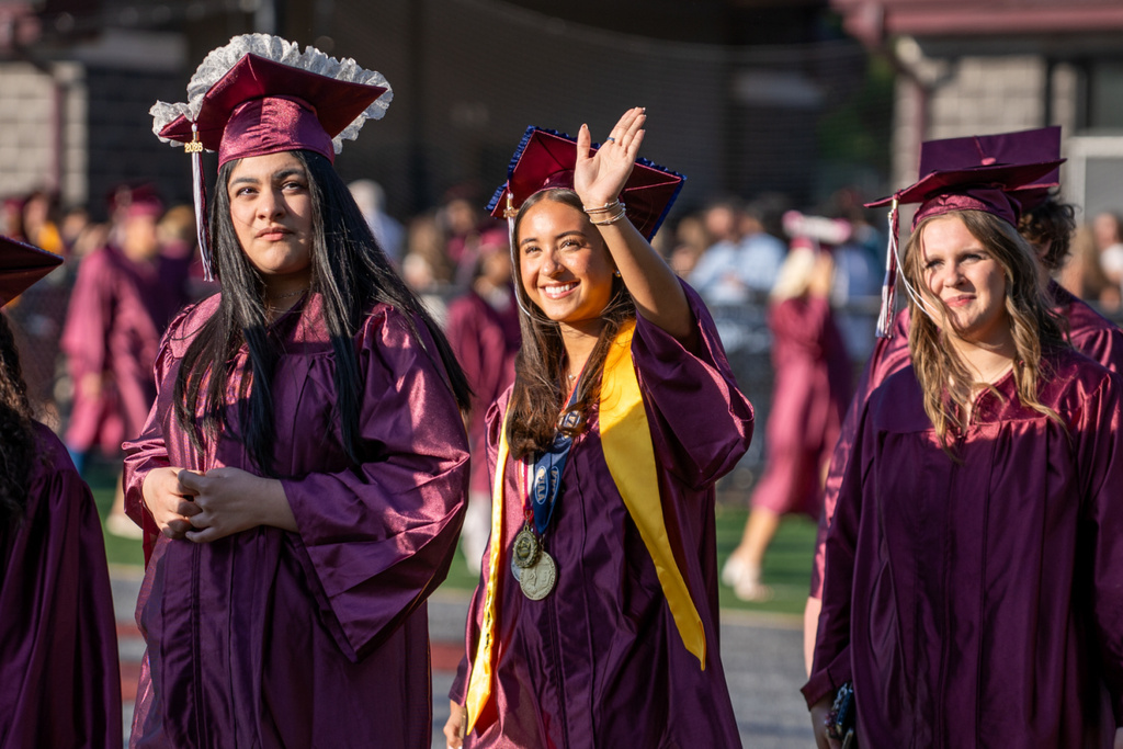 A graduate proudly waves to her supporters.