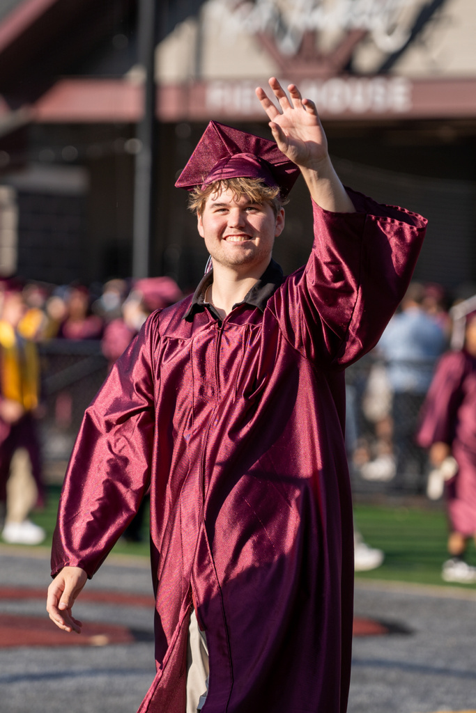 A graduate proudly waves to his supporters.