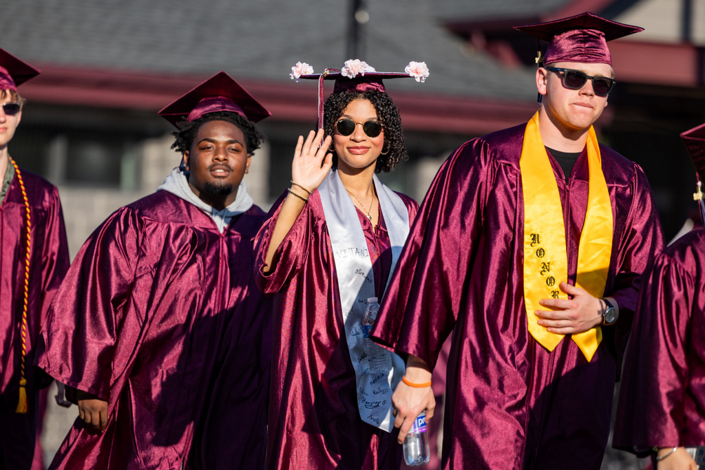 A graduate proudly waves to her supporters.