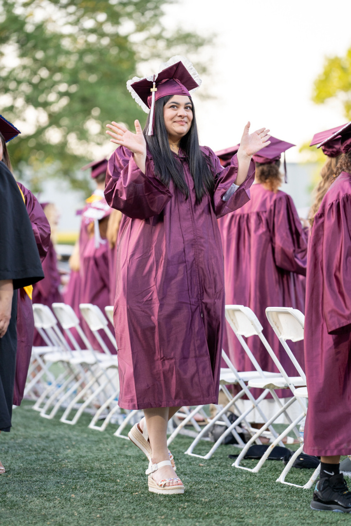 A graduate proudly waves to her supporters before receiving her diploma.