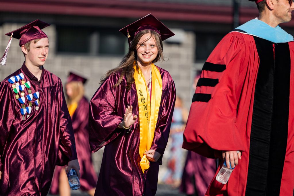 A graduate proudly waves to her supporters.