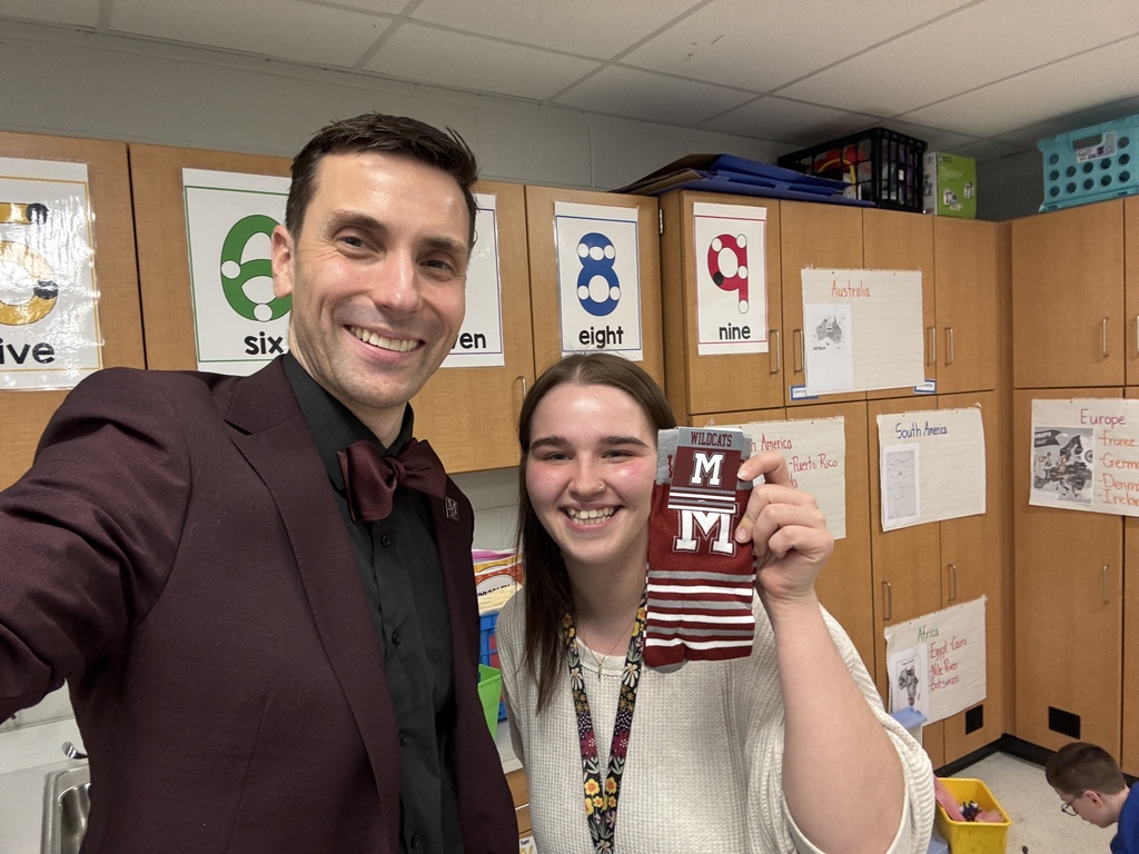 A man in a suit stands next to a woman who is holding a pair of branded socks.