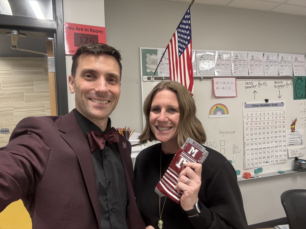 A man in a suit takes a selfie with a woman who is holding a pair of branded socks.