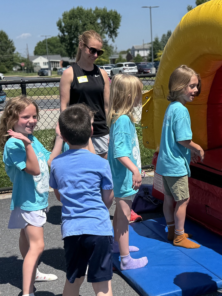 An adult chaperones young students waiting in line for a bouncy house.