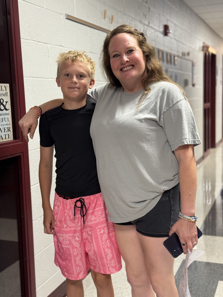 A mom stands with her arm around her son.