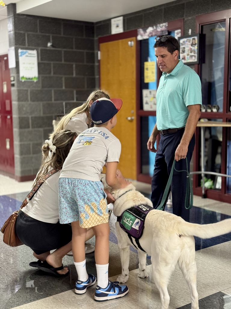 A family pets a facility dog with white fur.