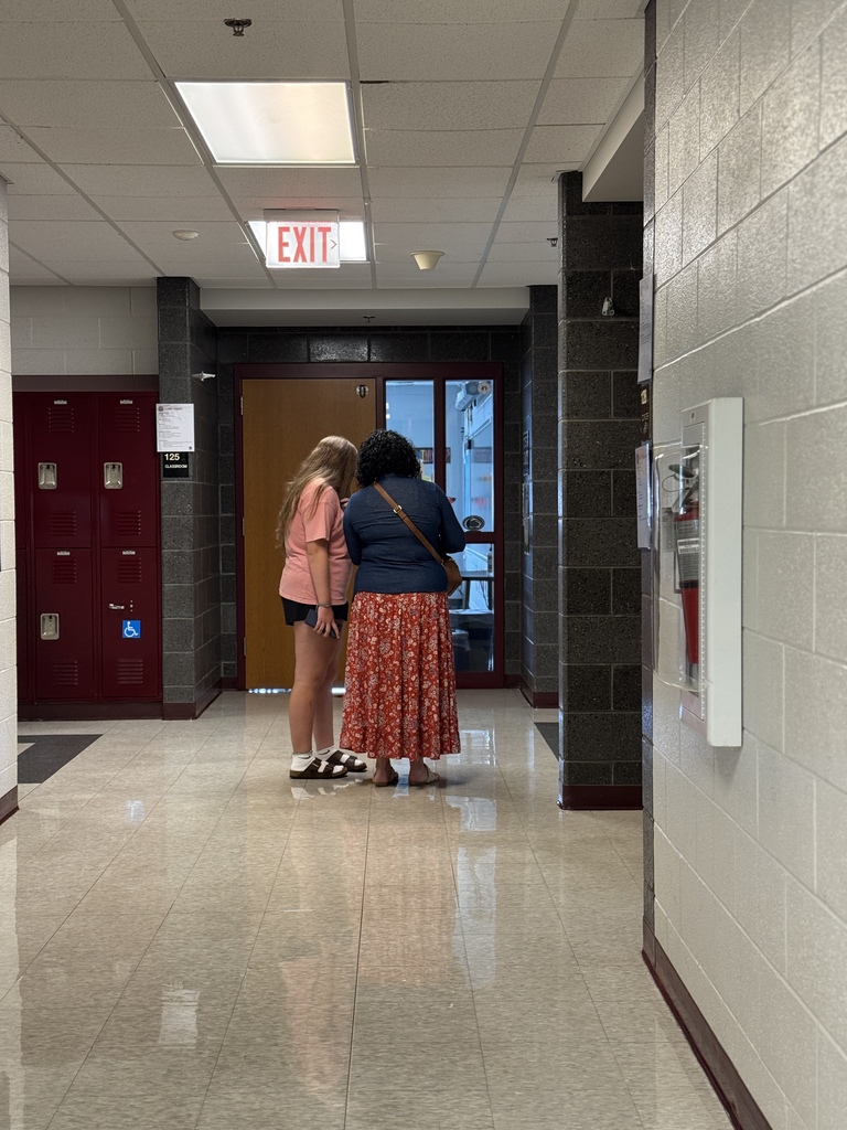 A woman and student stand down a hallway looking at a schedule.